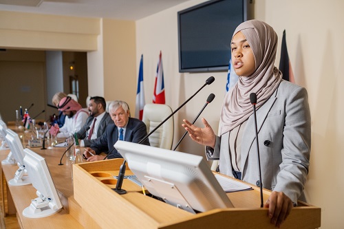 Image d'une femme portant un foulard s'adressant à une foule pour illustrer l'importance de la formation aux médias proposée par l'agence SmartCuts Creative à Lausanne et à Genève.