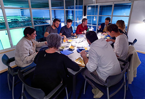Image showing a group of people eating in a lounge to illustrate the amenities offered by the SmartCuts creative agency studio in Lausanne and Geneva, Switzerland for the purposes of creative communication.